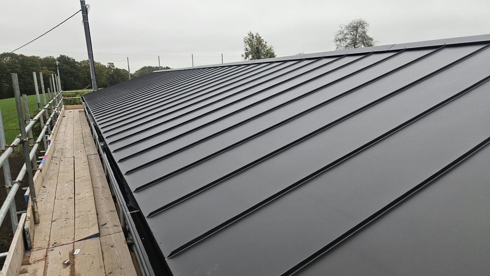 The black standing seam roof going on