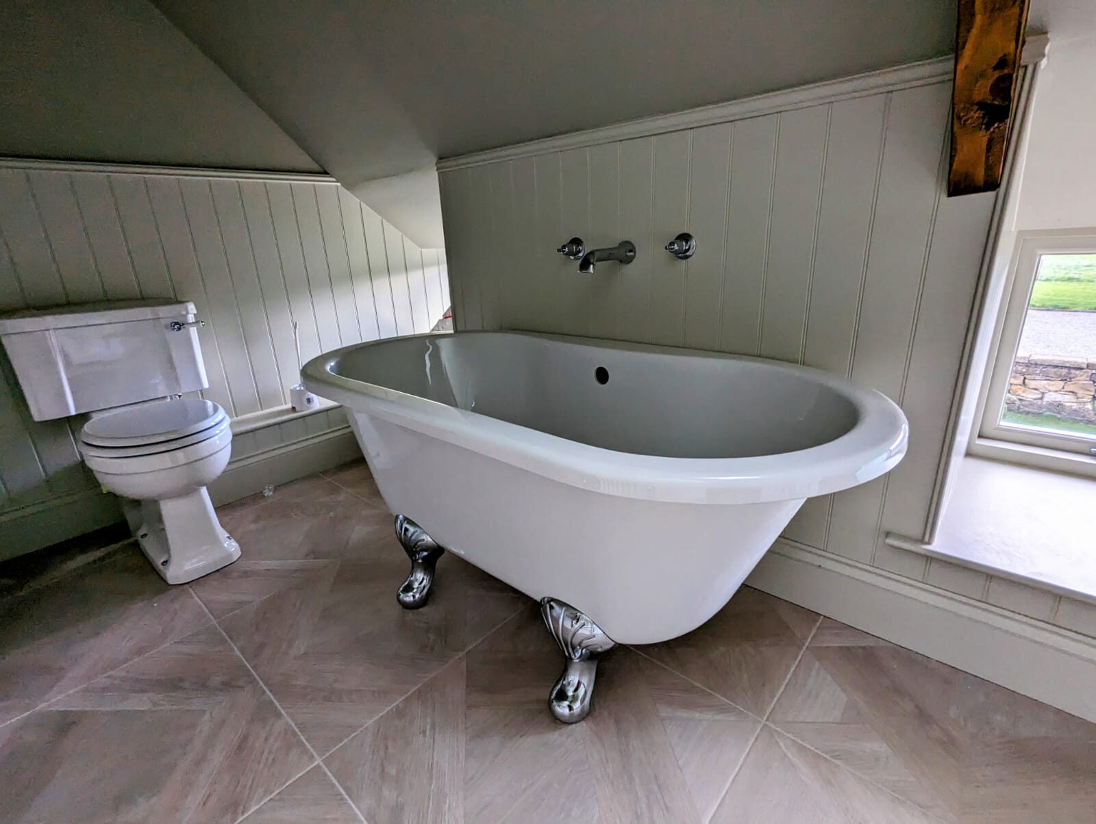 A roll top bath set under the eaves with panelled walls.