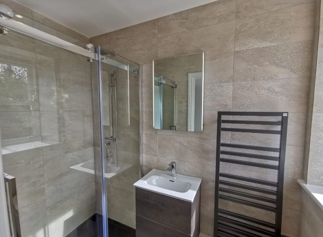 A walk in shower tiled in stone effect porcelain.