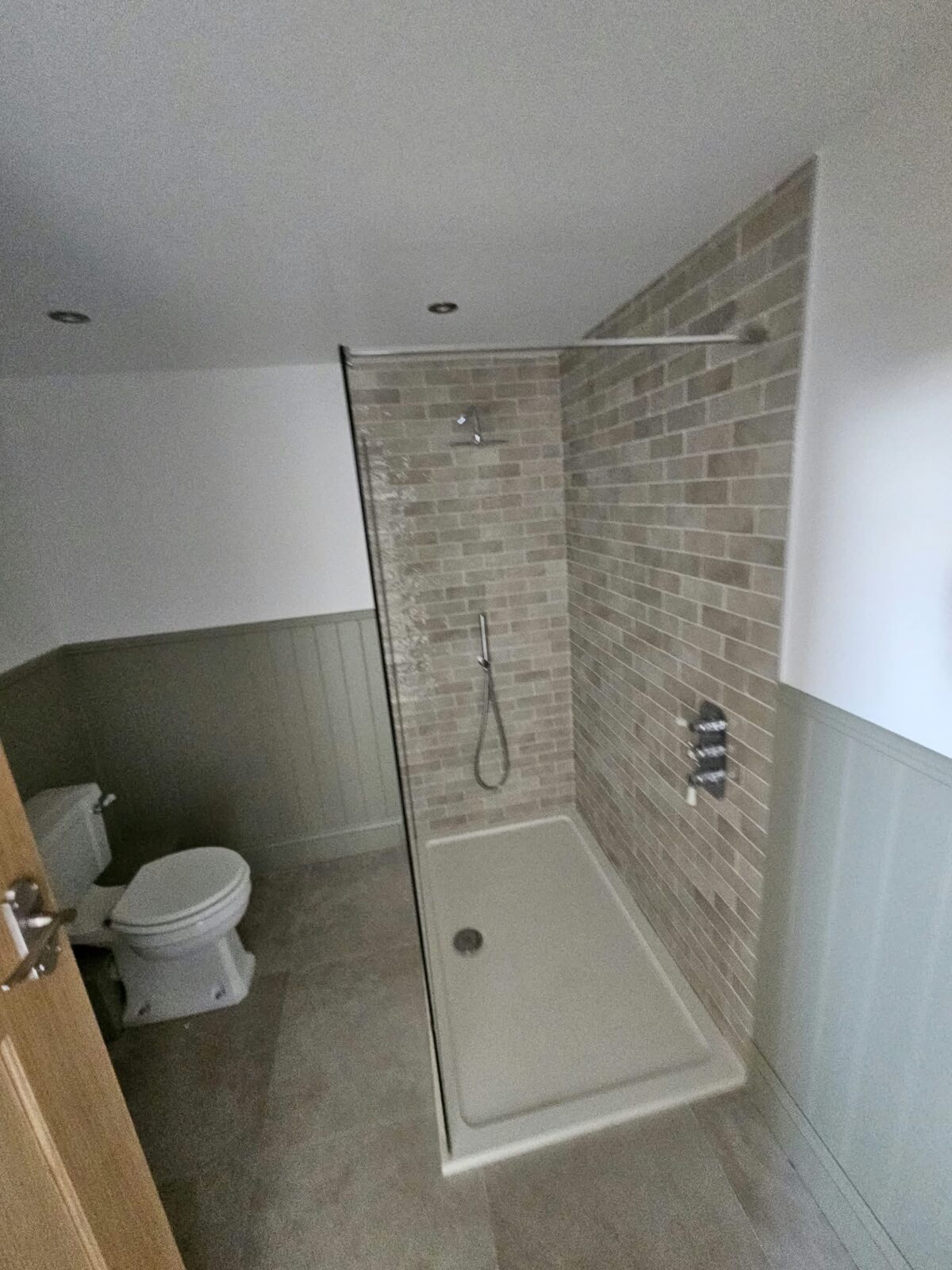 A walk in shower beside a panelled wall.