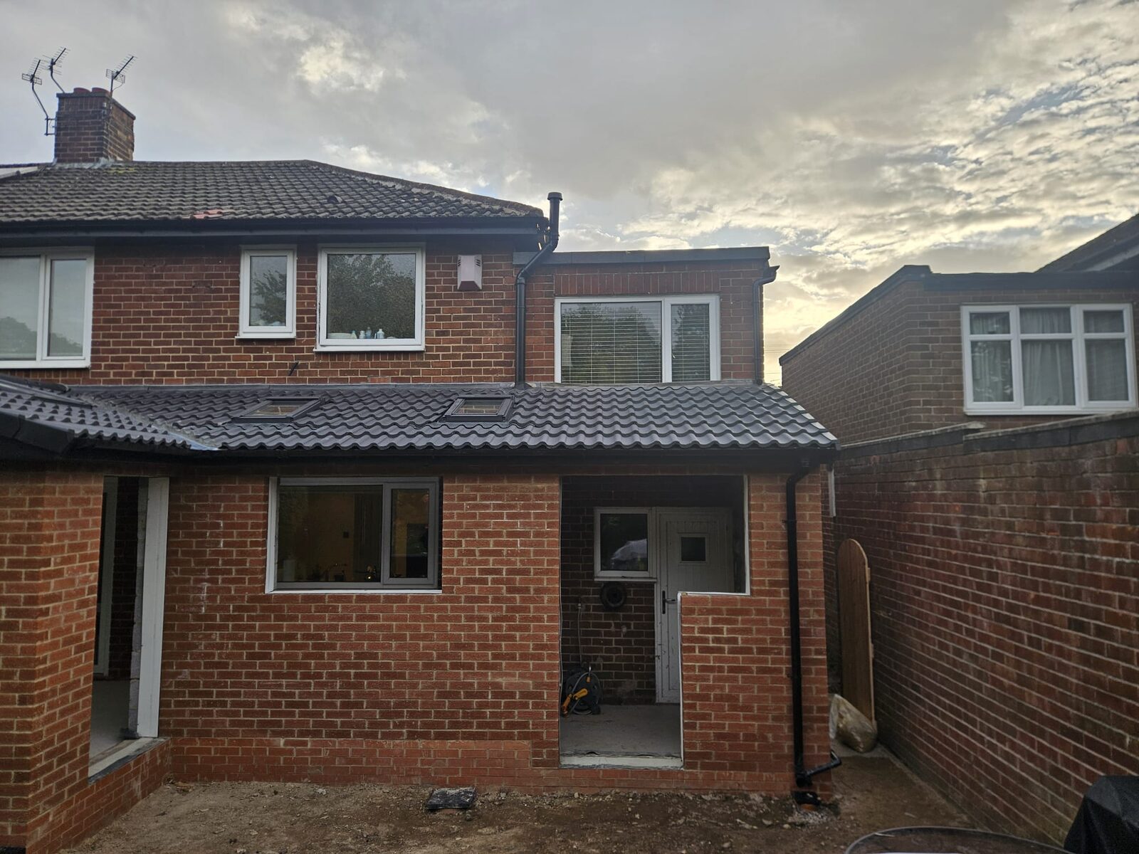 A two storey rear extension with the roof on and the door and windows fitted, the ground still to finish.
