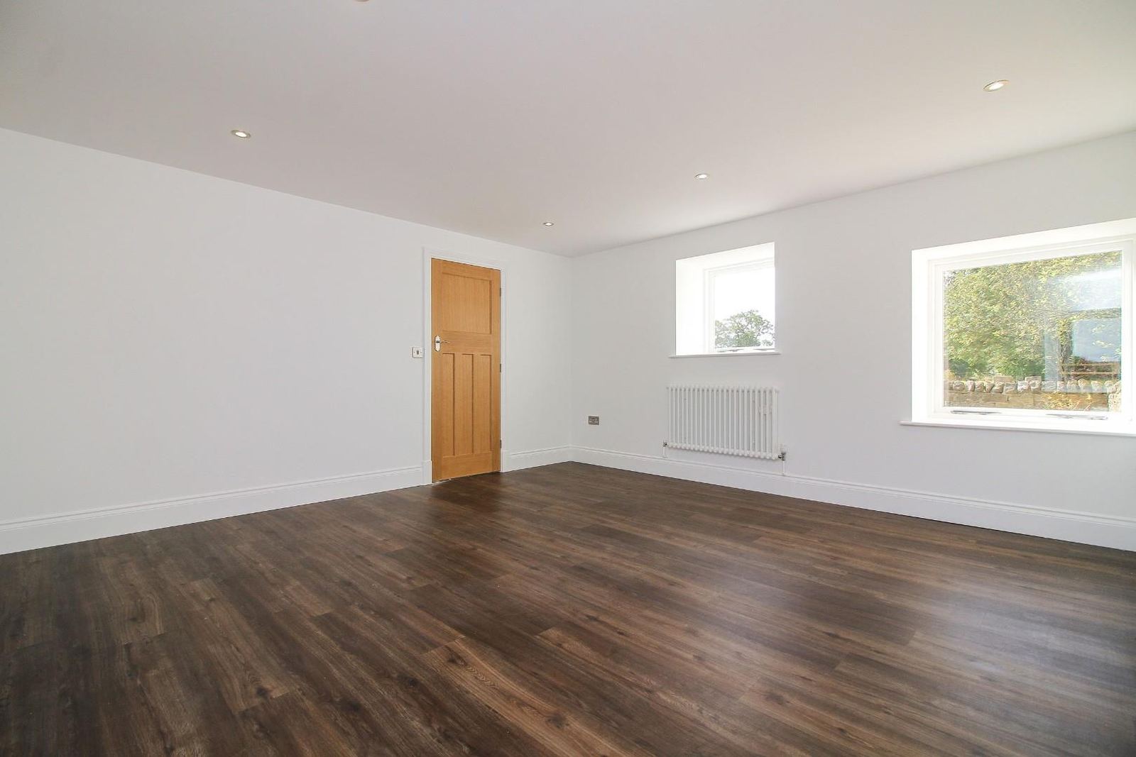 A converted garage, plastered and painted, with a wooden floor.